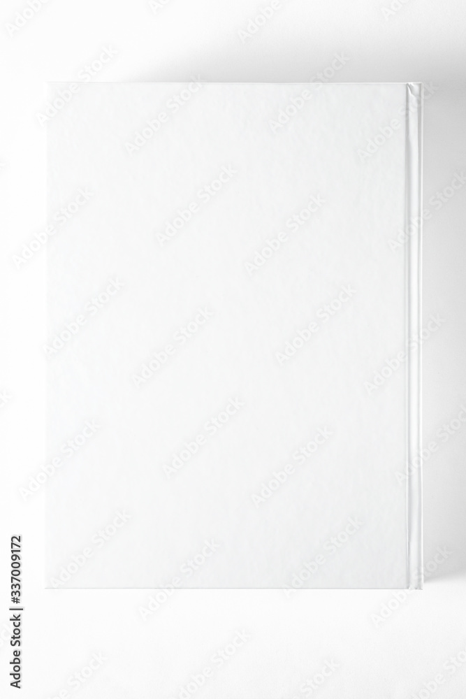 Mockup of closed blank square book at white textured paper background Mockup of closed blank square book at white textured paper background