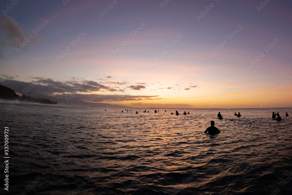 surfers waiting for waves at sunset on the sea