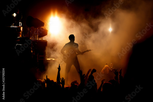 Silhouette of the guitarist on stage over the fans. photo