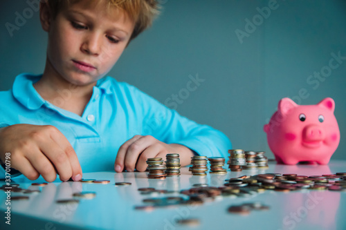 child saving money, boy put coins into piggy bank