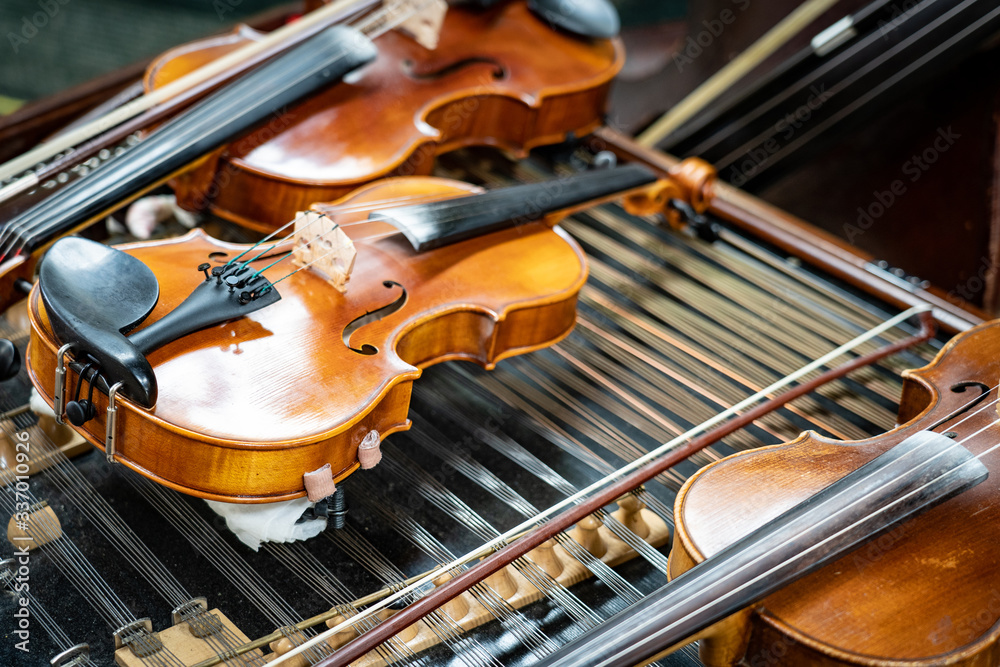 Fototapeta premium Antique violin and violin bow lying on dulcimer. Close up a violin instrument and cymbal before a concert. Music concept background