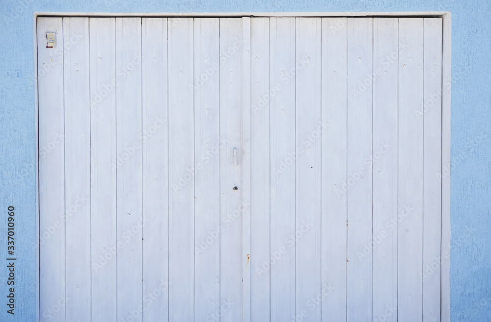 Wooden white gate made of vertical boards on a blue wall background Wooden white gate made of vertical boards on a blue wall background