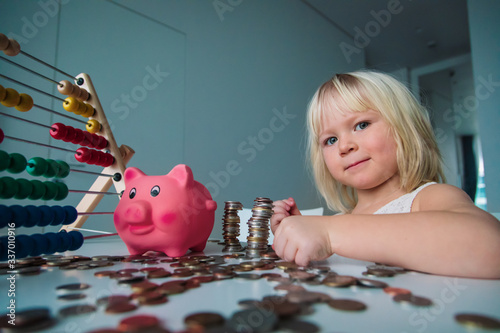 child counting coins and saving money, girl put coins into piggy bank