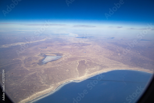 The shore of the sea lake from the porthole of an airplane on a sunny day.