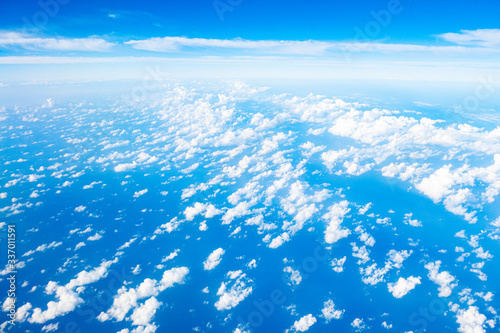 Beautiful clouds top view on a background of blue sky from the porthole of an airplane at altitude.