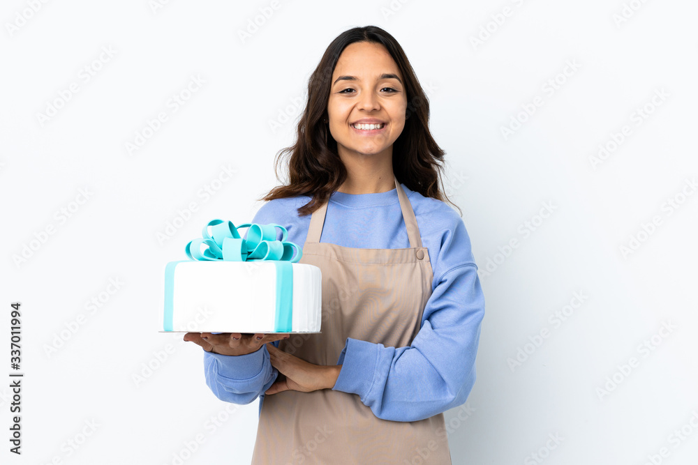 Pastry chef holding a big cake over isolated white background keeping the arms crossed in frontal position Pastry chef holding a big cake over isolated white background keeping the arms crossed in frontal position