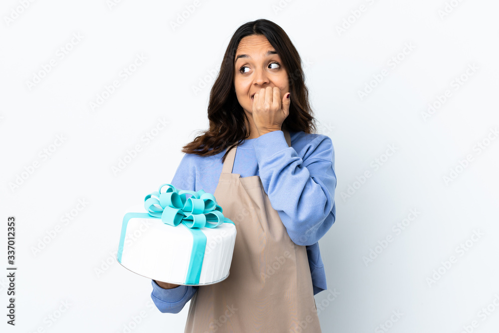 Pastry chef holding a big cake over isolated white background nervous and scared putting hands to mouth Pastry chef holding a big cake over isolated white background nervous and scared putting hands to mouth