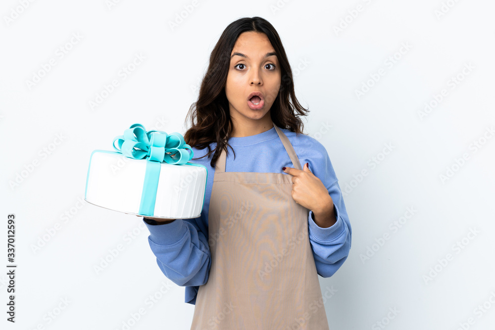 Pastry chef holding a big cake over isolated white background pointing to oneself Pastry chef holding a big cake over isolated white background pointing to oneself