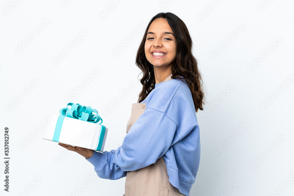 Pastry chef holding a big cake over isolated white background with arms crossed and looking forward