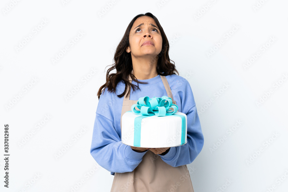 Pastry chef holding a big cake over isolated white background keeps palm together. Person asks for something Pastry chef holding a big cake over isolated white background keeps palm together. Person asks for something