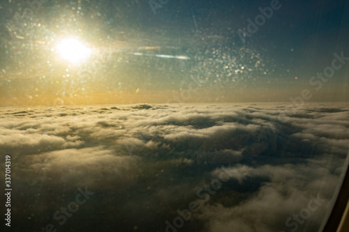 The sun above the clouds view from the porthole of an airplane on a sunny day.