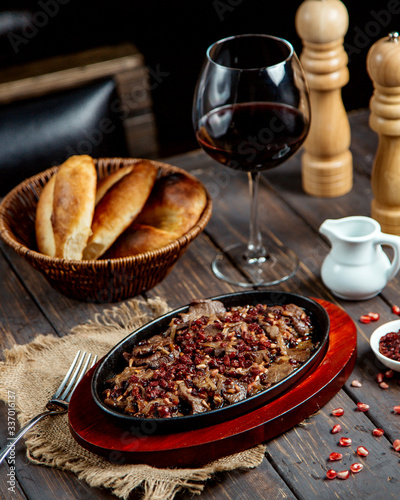 fried meat with pomegranate and glass of red wine