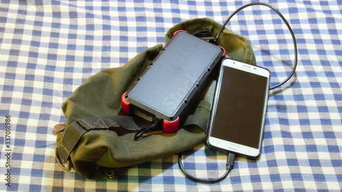 survival pouch and solar power bank usine alternative energy to recharge a mobile phone to make emergency calls