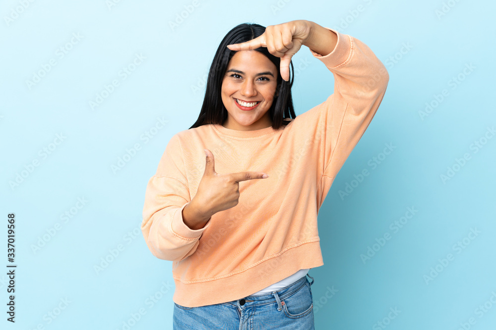 Young latin woman woman isolated on blue background focusing face. Framing symbol Young latin woman woman isolated on blue background focusing face. Framing symbol