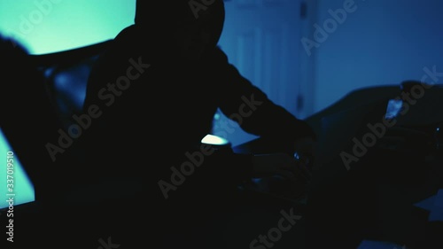 A computer programmer or hacker prints a code on a laptop keyboard to break into a secret organization system.