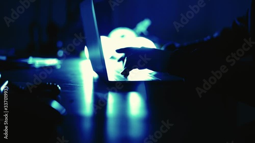 A computer programmer or hacker prints a code on a laptop keyboard to break into a secret organization system.