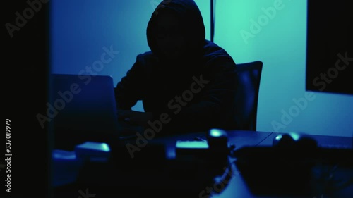 A computer programmer or hacker prints a code on a laptop keyboard to break into a secret organization system.