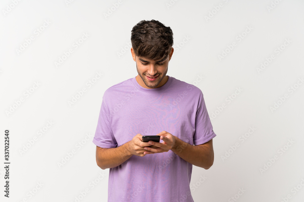 Young handsome man over isolated white background sending a message with the mobile Young handsome man over isolated white background sending a message with the mobile