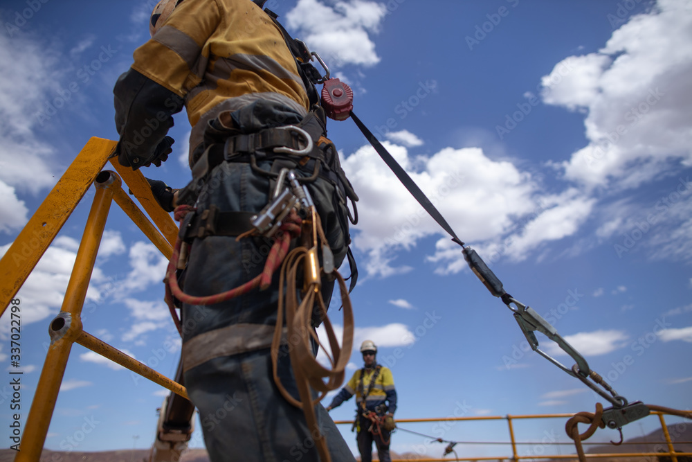 Safe workplace rigger wearing working at heights harness clipping an inertia  reel shock absorbing fall arrest