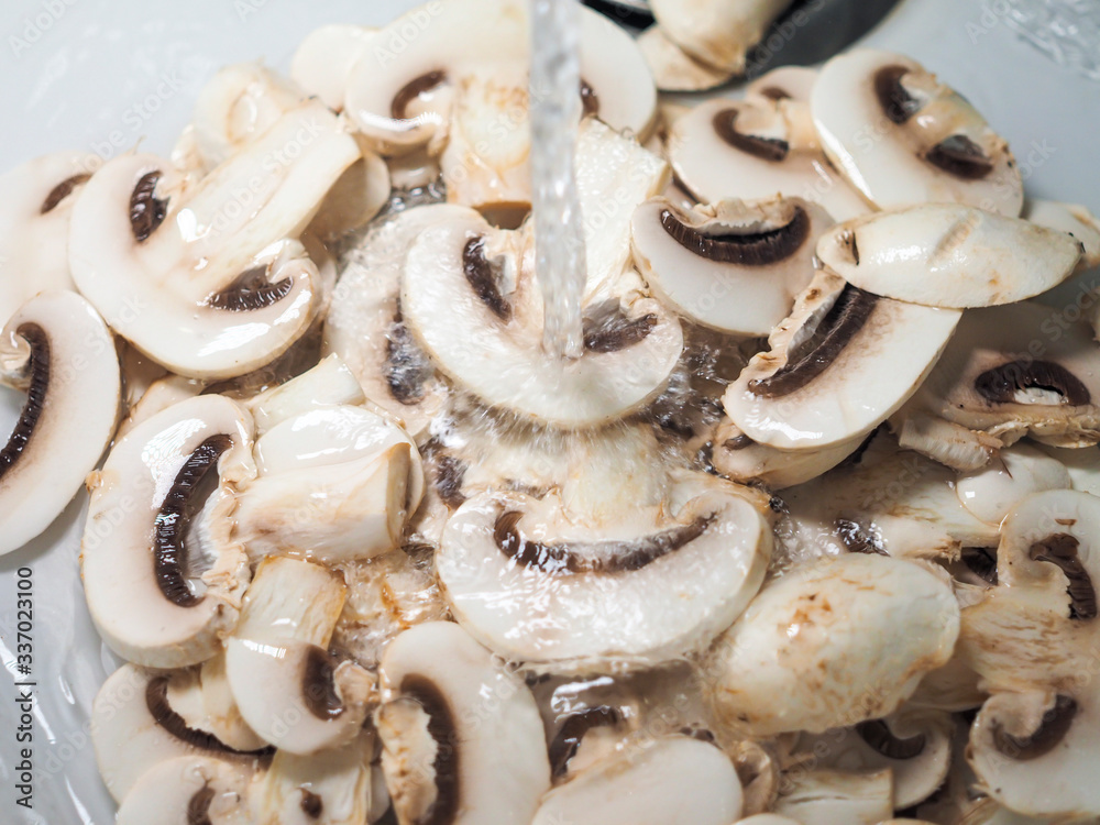 Sliced white champignons washed in water and ready for cook Sliced white champignons washed in water and ready for cook