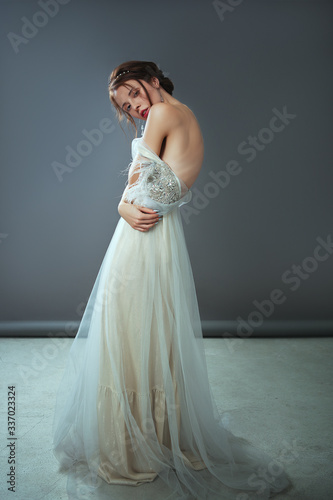 Emotional old-fashioned portrait of a girl in retro style in a light transparent dress with shiny elements on the shoulders.