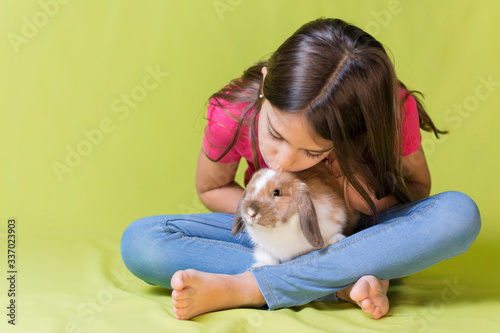 Little girl kissing her pet rabbit