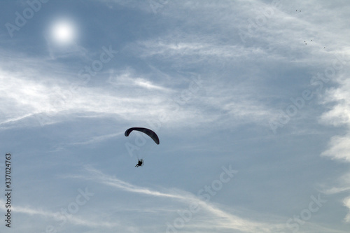 paraglider in the sky,motorized,cloud, flight,blue, fly,fun,freedom, air, white, sun, wings, parachute, wing, high, light, paragliding 