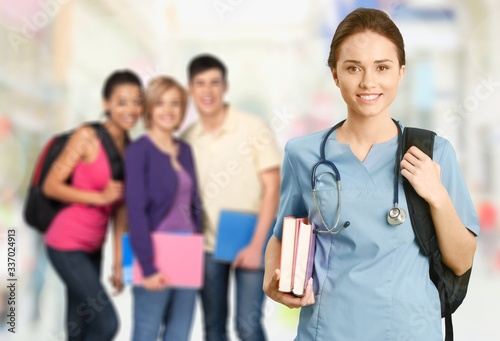 Nurse student with books and stethoscope on classmates background