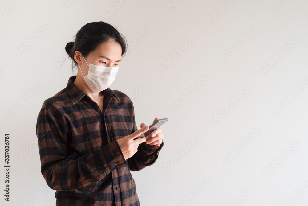 Asian young woman using smart phone wearing face mask protect air pollution, particulates and for protection flu.Coronavirus (COVID-19) outbreak prevention. Health care concept Asian young woman using smart phone wearing face mask protect air pollution, particulates and for protection flu.Coronavirus (COVID-19) outbreak prevention. Health care concept