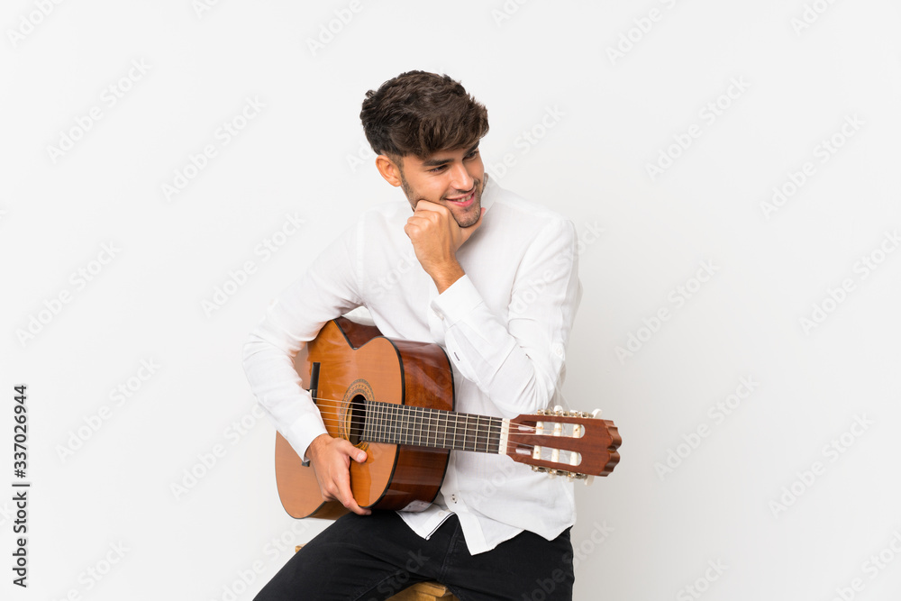Young handsome man with guitar over isolated white background looking side Young handsome man with guitar over isolated white background looking side