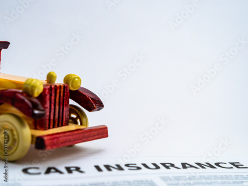 A vintage car toy with insurance document on the ground, shot on white background with copy space. photo