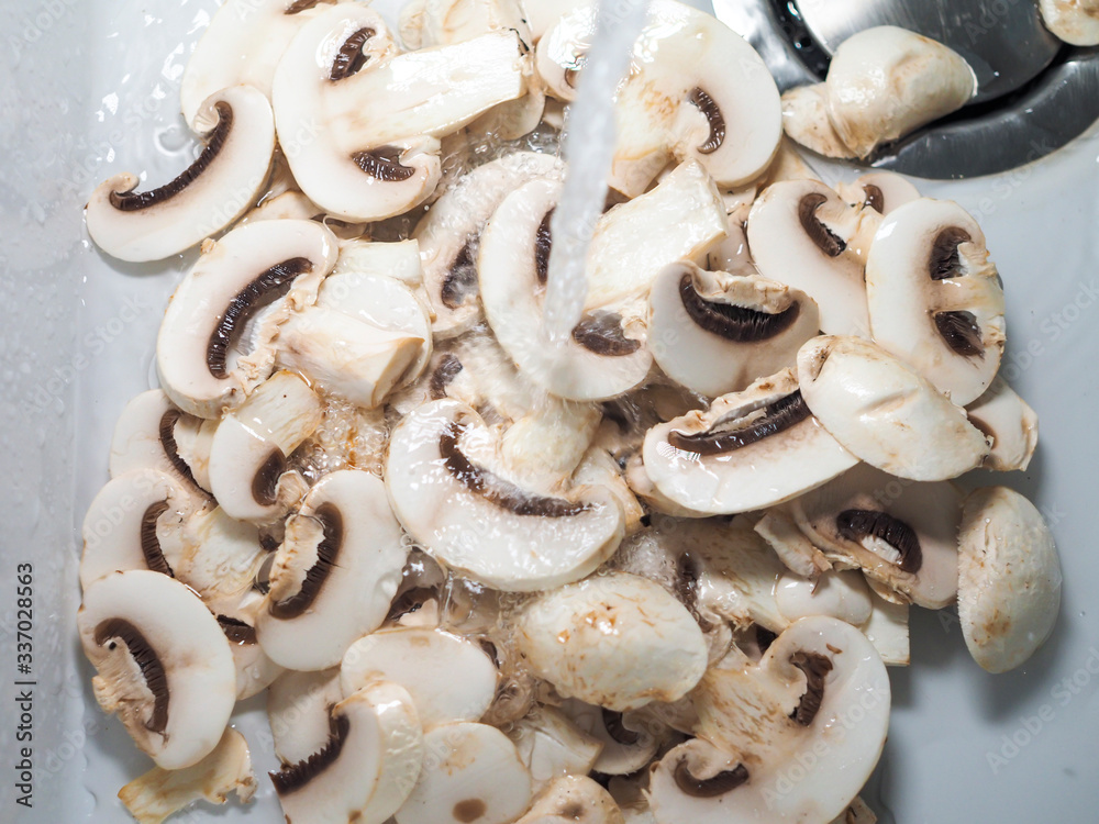 Sliced white champignons washed in water and ready for cook Sliced white champignons washed in water and ready for cook