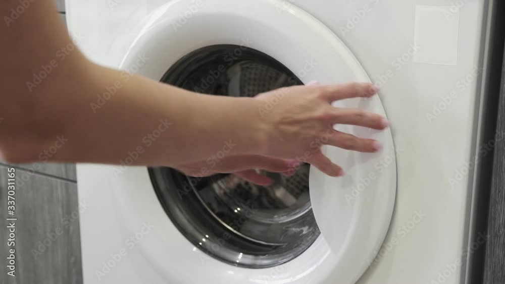 Female hand put WHITE TOWEL in laundry machine. Loading washing machine. Load clothes to washer machine. Load clothes laundry washing machine. Preparing laundry washing Female hand put WHITE TOWEL in laundry machine. Loading washing machine. Load clothes to washer machine. Load clothes laundry washing machine. Preparing laundry washing