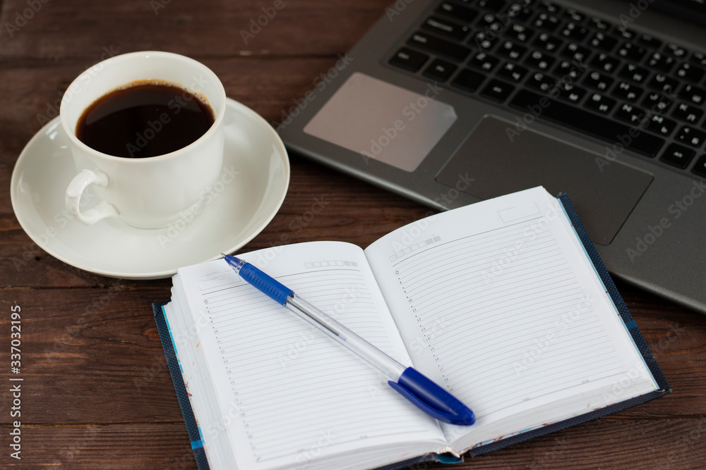 Notebook, notepad for notes and a cup of coffee on a dark wooden table. Remote work during quarantine. Notebook, notepad for notes and a cup of coffee on a dark wooden table. Remote work during quarantine.