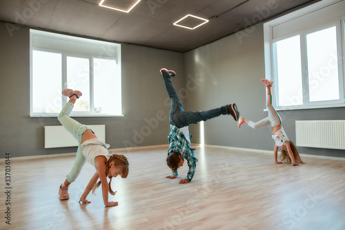 Fototapeta Naklejka Na Ścianę i Meble -  Breakdance battle. Little boys and girls learning how to stand on hands while having a choreography class in the dance studio