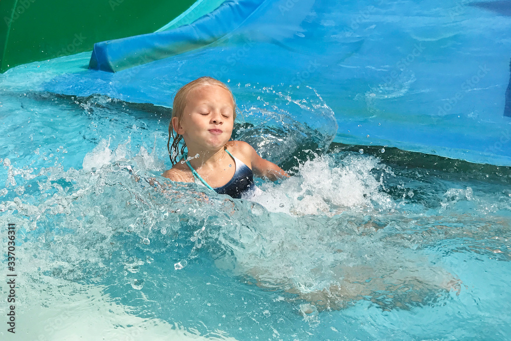 Little girl on water slide at aquapark. Stock Photo | Adobe Stock