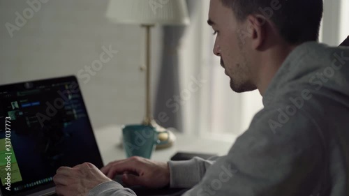 Work from home. A young white man working on the laptop at home side view