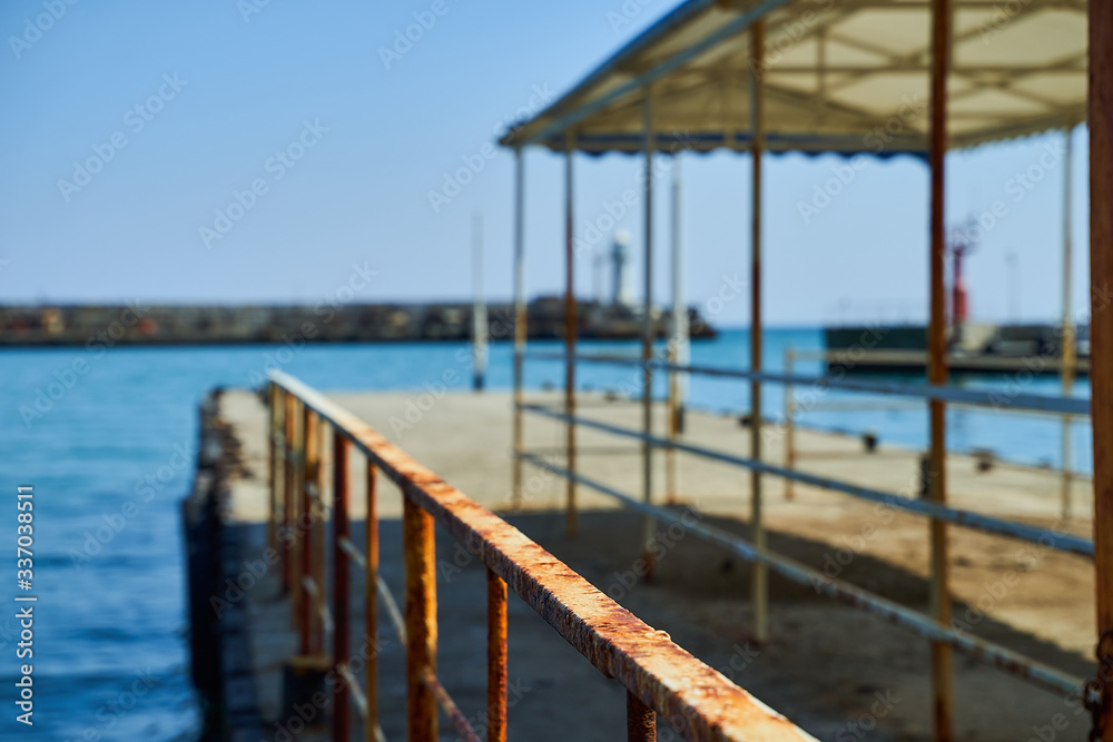 Lighthouse on the background of the sea and the sky, the sea is full calm and clear clear sky, spring. Lighthouse, sea and pier.