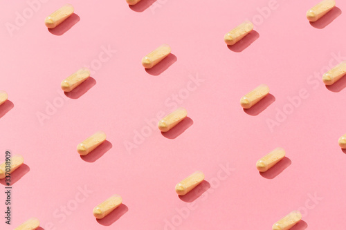 Yellow medicine pills flat laid inside the pattern, on top of colorful pink background.