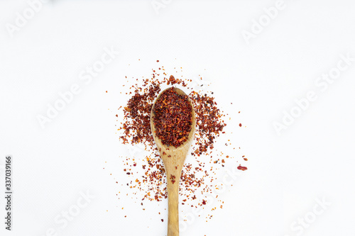 
chili peppers powder on wooden spoon isolated top view