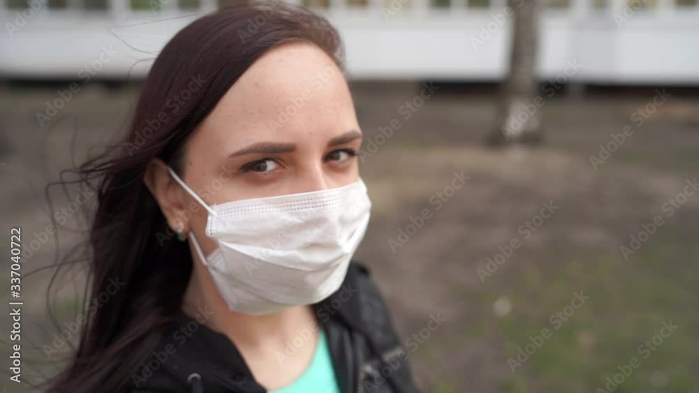 Portrait of young woman in medical mask on her face standing on street. Adult female covered her face with mask to protect yourself from diseases. Portrait of young woman in medical mask on her face standing on street. Adult female covered her face with mask to protect yourself from diseases.