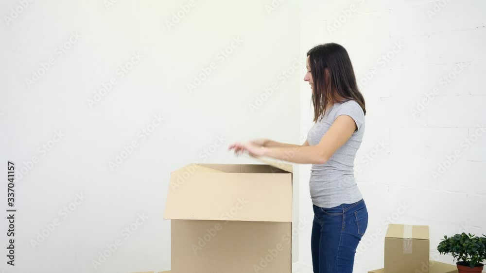 Happy satisfied woman upacking carton box, pulling out clothes with great excitement. Happy satisfied woman upacking carton box, pulling out clothes with great excitement.