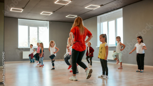 Fototapeta Naklejka Na Ścianę i Meble -  Dance for kids. Group of little boys and girls dancing while having choreography class in the dance studio. Dance teacher and children