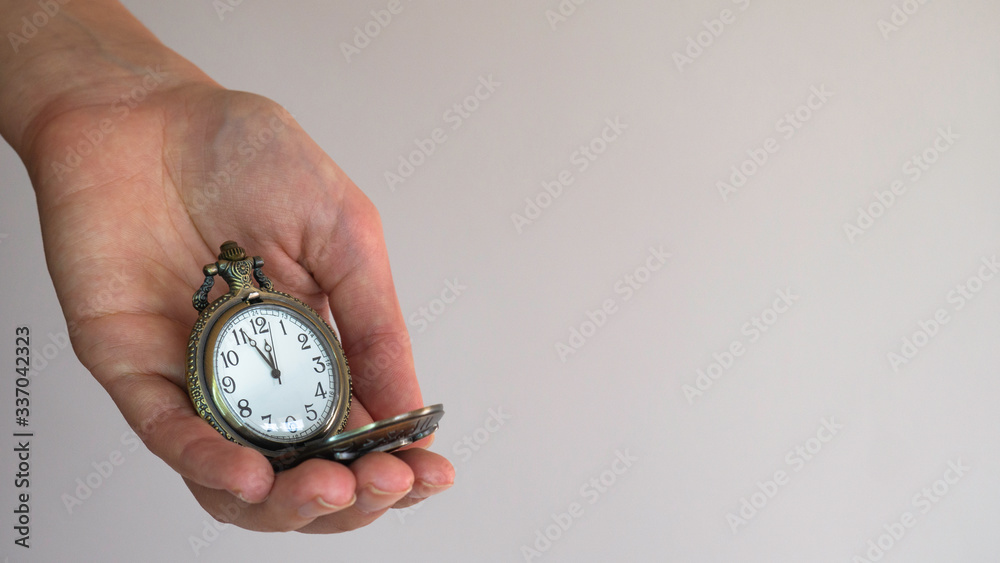 An old pocket watch in a woman's hand shows 5 minutes to 12 o'clock. Negative space. Copy space for text. An old pocket watch in a woman's hand shows 5 minutes to 12 o'clock. Negative space. Copy space for text.