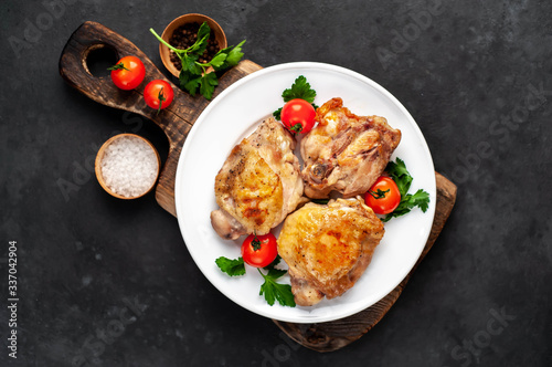 grilled chicken thighs on a white plate with spices on a stone background