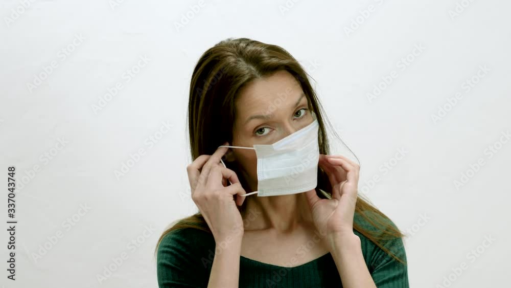 Portrait of an young girl looking at the camera and putting on her face a surgical face mask. Protective measures against allergy and virus. 4K Portrait of an young girl looking at the camera and putting on her face a surgical face mask. Protective measures against allergy and virus. 4K