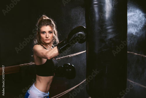 Young sports woman hitting a punching bag. Boxing training hard on the ring in gym.