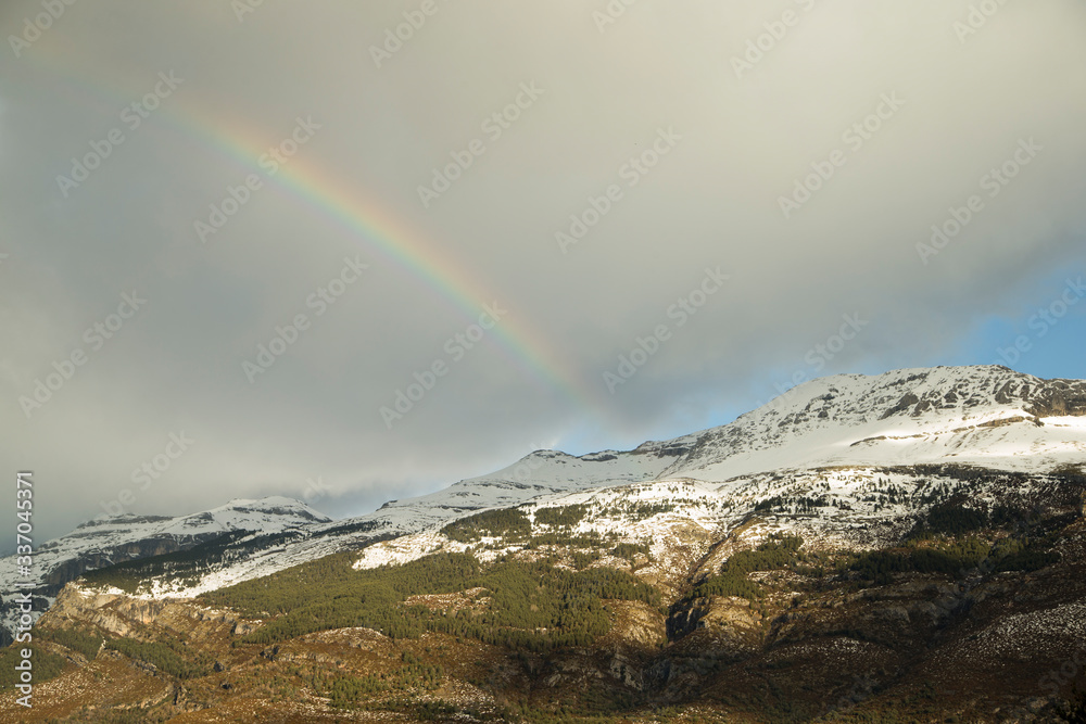 Image of snowy mountains with a rainbow.