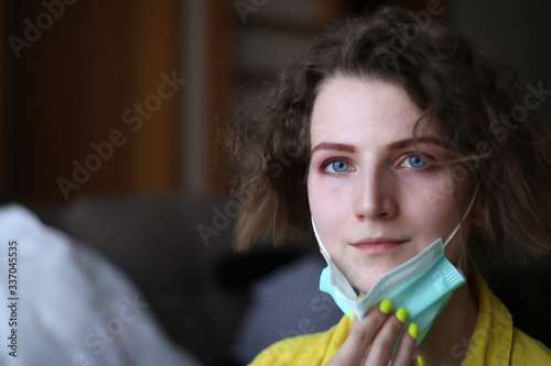 Young woman putting on medical mask. Caucasian woman with short hair and make-up protecting herself from viruses