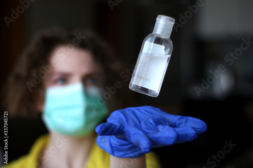 Catching bottle of sanitizer durring deficit. Washing hands with sanitizer, wearing medical mask and gloves